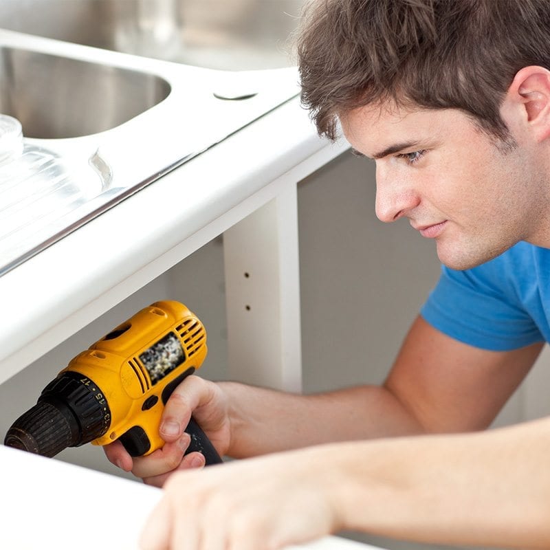 Image of a tradesman screwing a cabinet